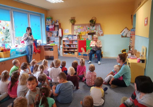 Dzieci siedząc na dywanie słuchają opowiadania