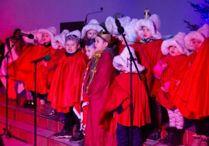 Dzieci z grupy siódmej w czerwonych peleryach śpiewją kolęde