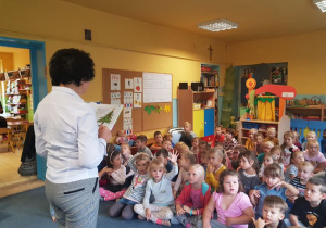 Dzieci słuchają opowiadania czytanego przez gościa